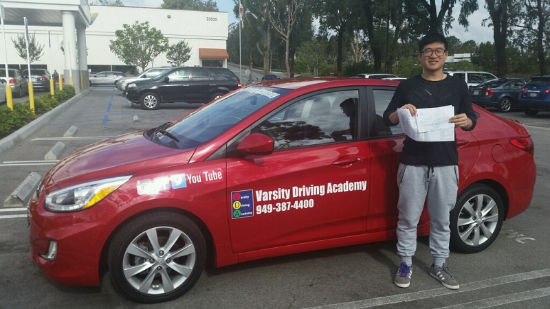Where to Take Driving Lessons in Huntington Beach Student Standing Next to a Training Vehicle